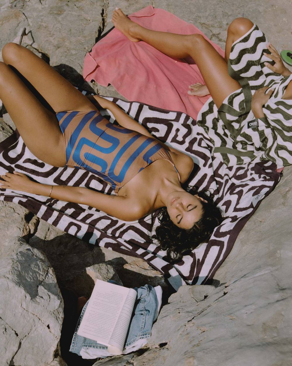 A blue and white towel hanging on a chair on a cobblestone beach. In the background you can see similar red chairs standing around.